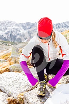 Runner tying sport shoe in mountains on trail