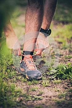 Runner tying sports shoe on trail