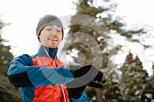 Runner wearing warm sporty clothes in headphones looks at a modern smart clock