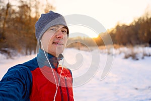 Runner wearing warm sporty clothes in headphones take selfie