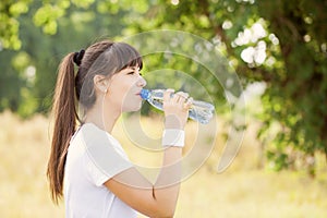 Runner woman drinking water after jogging