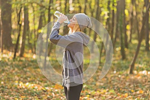 Runner woman drinking water in the park