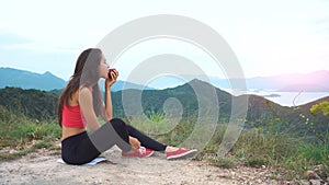 Runner woman eat apple on mountain peak