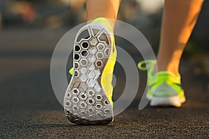 Runner woman feet running on road closeup on shoe. Female fitness model sunrise jog workout. Sports lifestyle concept.