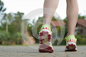 Runner woman feet running on road closeup on shoe. Female fitness athlete jogger workout in wellness concept at sunrise. Sports
