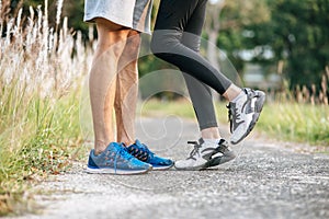 Runner woman and man feet running on road closeup on shoe. Sports healthy lifestyle concept