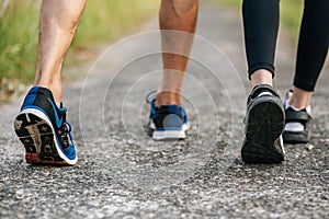 Runner woman and man feet running on road closeup on shoe. Sports healthy lifestyle concept