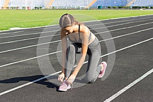 Runner women tying shoes laces getting ready for race on run track in stadium sport and fitness concept