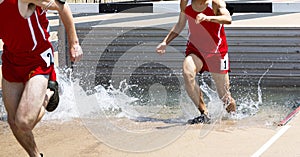 Runners splashing in the steeplechase pet during a track race
