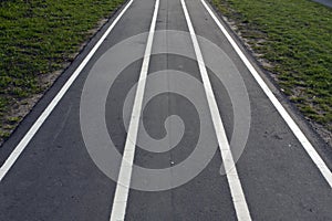 Running asphalt track with white painted lines.