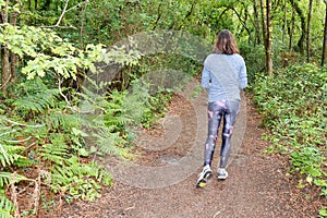 Running athlete behind rear view woman walking exercise healthy lifestyle concept in wooden pathway forest park