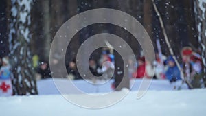 Running biathlon athletes in defocus on background of falling snow Slow motion