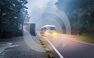 Running bus with light on local road inside tropical forest