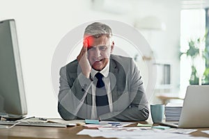 Running a business can be a real pain. Shot of a businessman with a headache holding his head while sitting at his desk.
