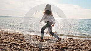 Running caucasian girl and her sweet siba inu puppy are playing ball near the sea slow motion