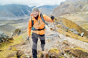 Running caucasian man with backpack and trekking poles by Makalu Barun Park route near Khare. Mera peak climbing acclimatization