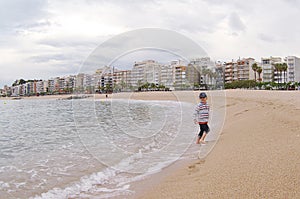 Running child on the beach. Amazing view on beach and sea. Blanes, Costa Brava, Catalonia, Spain