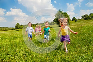 Running children in green field during summer