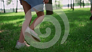 Running children legs on green grass meadow. Unknown kids play jogging outdoors.