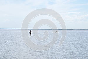 Running children on the surface of lake at summer. Salt shallow lake. Loneliness concept in big world