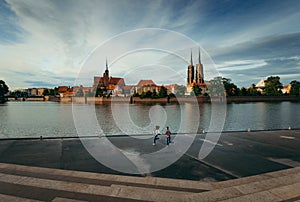 Running couple by the hand along the Ostrow Tumski in Wroclaw, Poland. Magnificent nature view.