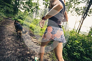 Running with a dog. Woman runner in green forest.