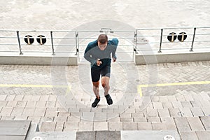 Running, energy and fitness man at stadium steps for workout, resilience or training challenge. Arena, stairs and top