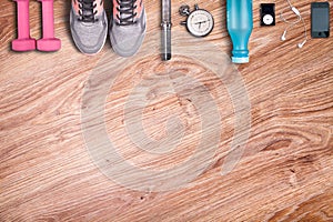 Running equipment. Dumbbells and running shoes, analog stopwatch and smartphone.