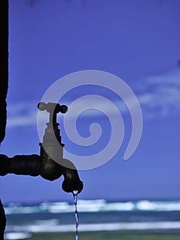 Running faucet with ocean in the background