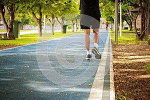 Running feet male in runner jogging exercise with old shoes for health lose weight concept on track rubber cover blue public park