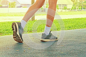 Running feet male in runner jogging exercise with old shoes for health lose weight concept on track rubber cover blue public park