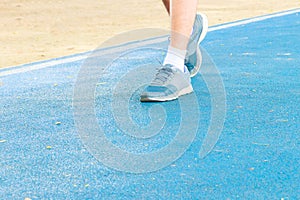running feet male in runner jogging exercise with old shoes for health lose weight concept on track rubber cover blue public park