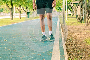 Running feet male in runner jogging exercise with old shoes for health lose weight concept on track rubber cover blue public park