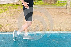 Running feet male in runner jogging exercise with old shoes for health lose weight concept on track rubber cover blue public park