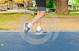 Running feet male in runner jogging exercise with old shoes for health lose weight concept on track rubber cover blue public park