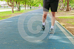 Running feet male in runner jogging exercise with old shoes for health lose weight concept on track rubber cover blue public park