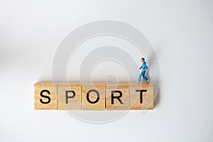 Running and Fitness concept. Runner miniature figure people run on wooden letter block wording sport on white background
