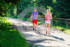 Running fitness couple of runners doing sport on road outdoor. Active living man and woman jogging training cardio