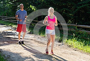 Running fitness couple of runners doing sport on road outdoor. Active living man and woman jogging training cardio