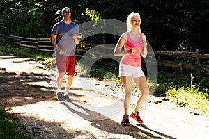 Running fitness couple of runners doing sport on road outdoor. Active living man and woman jogging training cardio