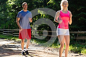 Running fitness couple of runners doing sport on road outdoor. Active living man and woman jogging training cardio