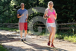 Running fitness couple of runners doing sport on road outdoor. Active living man and woman jogging training cardio