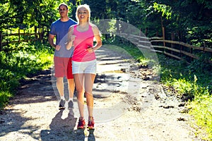 Running fitness couple of runners doing sport on road outdoor. Active living man and woman jogging training cardio