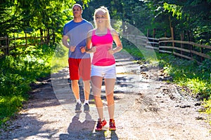 Running fitness couple of runners doing sport on road outdoor. Active living man and woman jogging training cardio