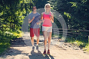 Running fitness couple of runners doing sport on road outdoor. Active living man and woman jogging training cardio