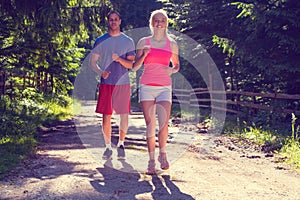 Running fitness couple of runners doing sport on road outdoor. Active living man and woman jogging training cardio