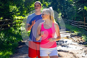 Running fitness couple of runners doing sport on road outdoor. Active living man and woman jogging training cardio