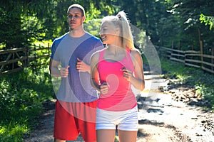 Running fitness couple of runners doing sport on road outdoor. Active living man and woman jogging training cardio