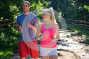 Running fitness couple of runners doing sport on road outdoor. Active living man and woman jogging training cardio