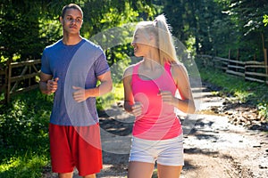 Running fitness couple of runners doing sport on road outdoor. Active living man and woman jogging training cardio